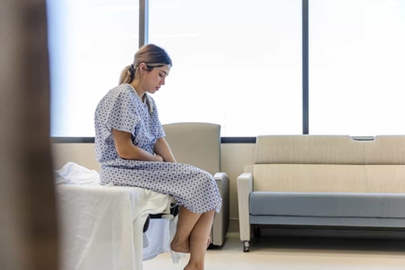 Female patient sits in a hospital room looking sad
