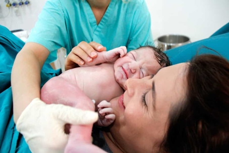Mother in hospital bed holds her newborn baby