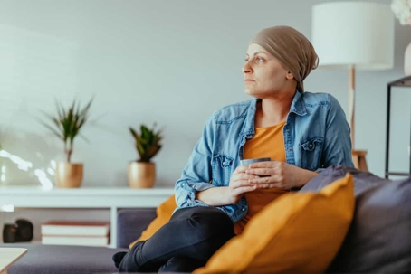 Cancer patient sits on the couch with a cup of tea