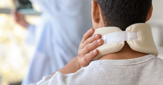 man with neck brace in hospital